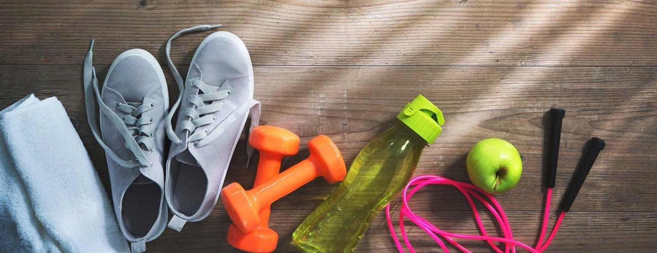 Jump rope, apple, water bottle, weights, tennis shoes and towel on the floor